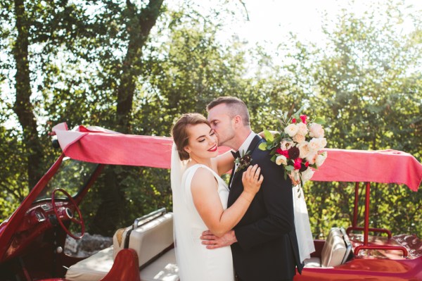 Bride and groom bouquet of flowers kissing on the cheek caddy car