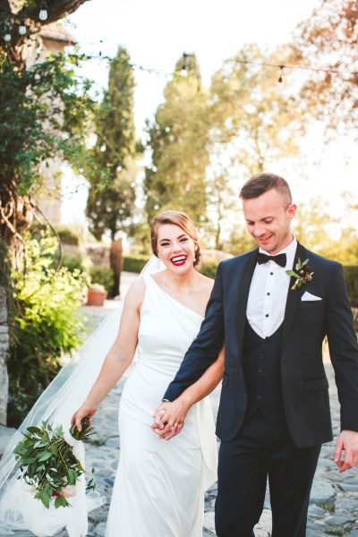 Bride and groom smiling laughing holding hands lights exterior photography shot flowers bouquet