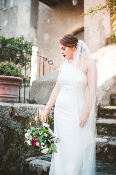 Bride holding bouquet of flowers looking down steps