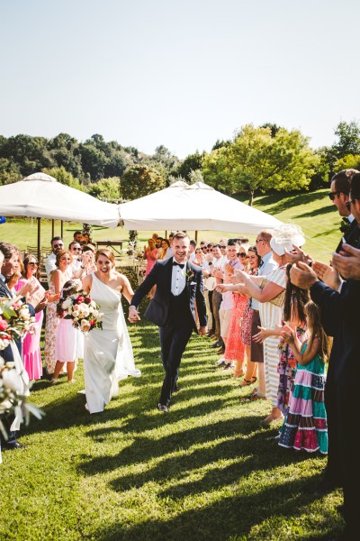 Just wed couple aisle guests clapping flowers exterior bouquet sunshine sunny