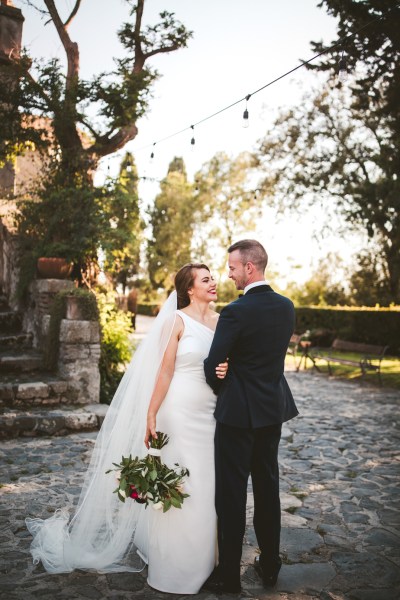 Bride groom couple shot exterior steps flowers bouquet dress veil