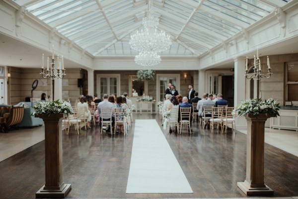 Interior ceremony wedding vows guests chandelier hanging flowers