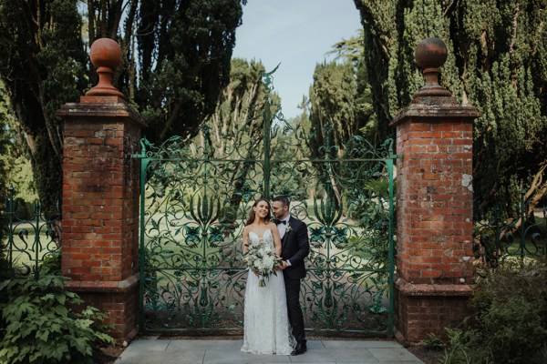 Couple photography exterior gate hold embrace bouquet of flowers