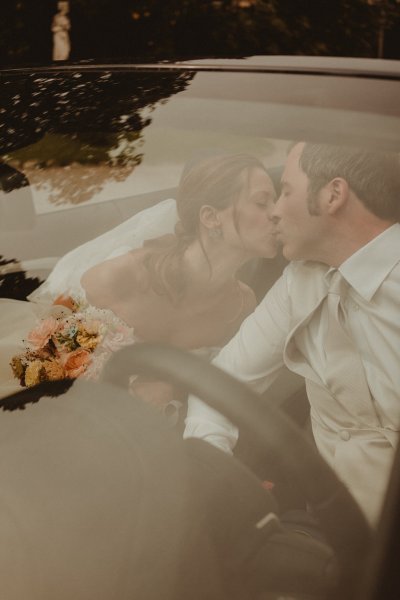 bride and groom kissing in car