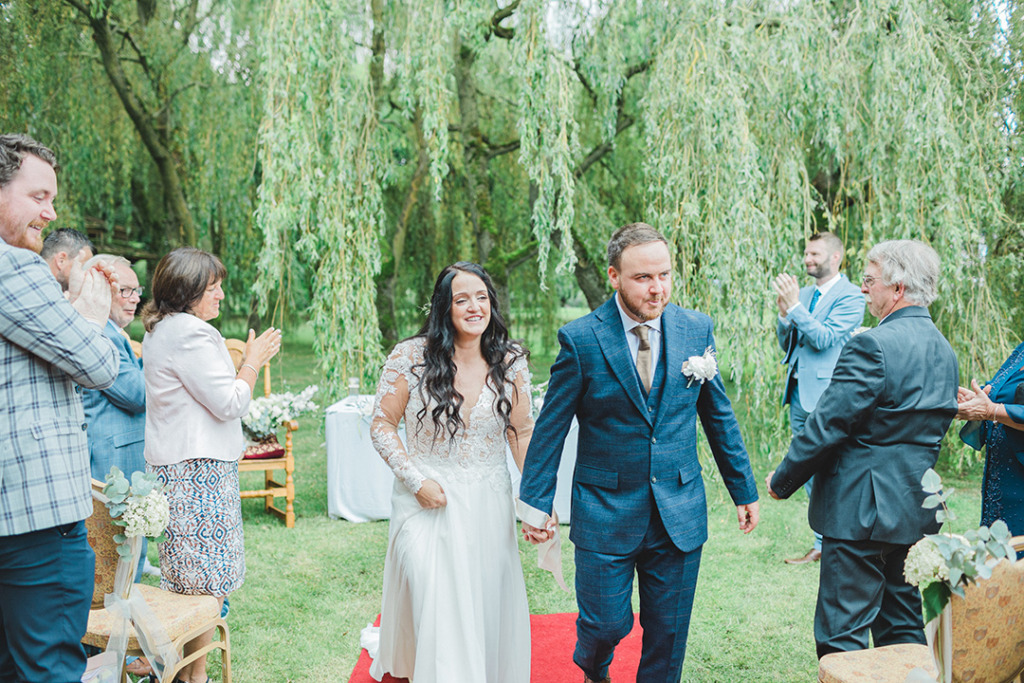 Walking down the aisle red carpet just wed couple bride groom clapping guests ceremony