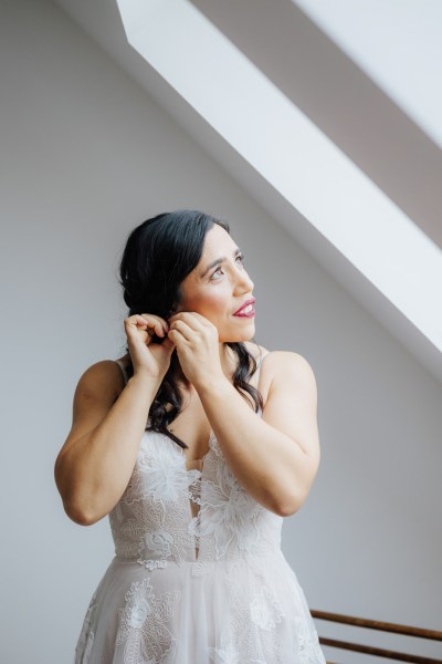 Bride putting on earring on morning of wedding Olga Hogan Photography: Hannah & Eoghan