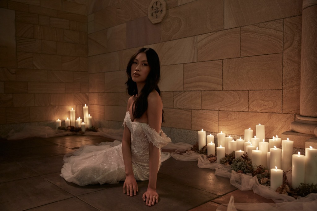 Sarai Dress model lying on church floor candles lighting veil