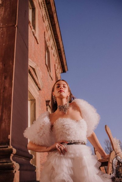 Close up of model wearing ruffled feather bridal gown from collection dress exterior home