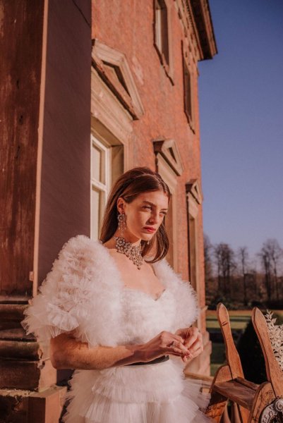 Close up of model wearing ruffled feather bridal gown from collection dress exterior home sunshine bright