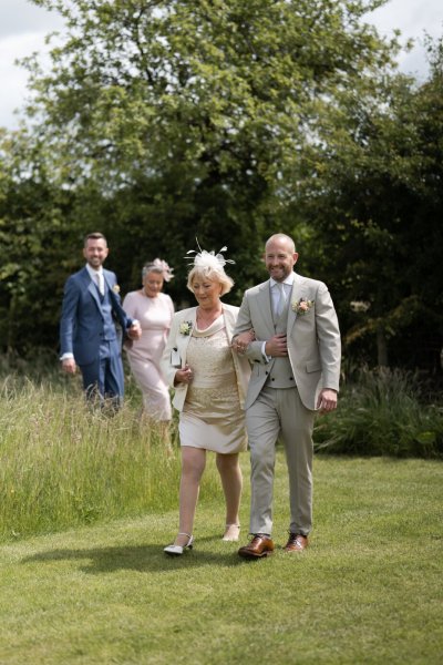 groom walking down the aisle with mothers