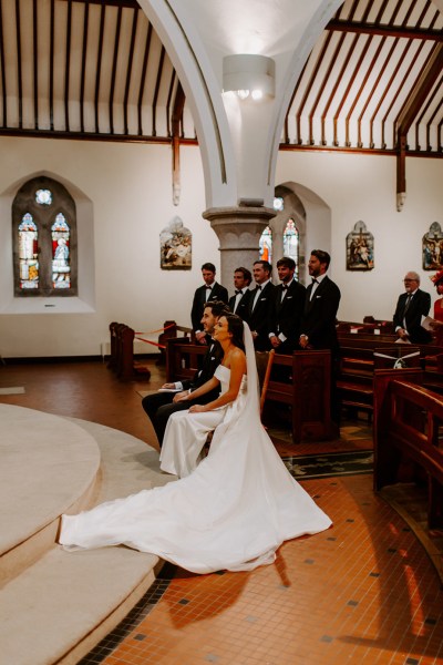 Church ceremony couple bride groom sitting in front of guests priest