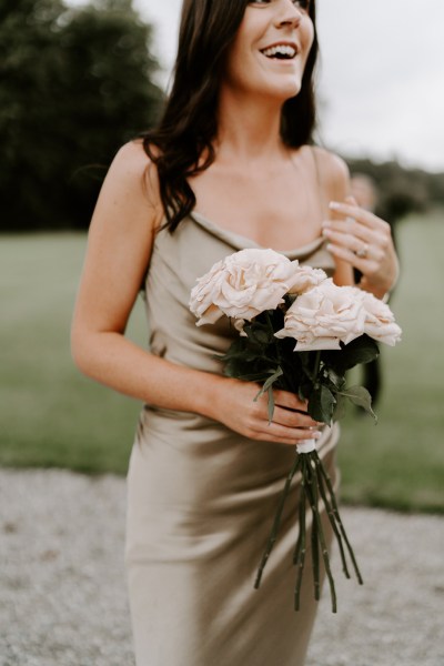 Bridesmaid holding pink roses flowers satin dress exterior shot