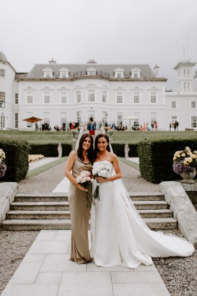 Bride and maid of honour long train dress white roses flowers bouquet exterior hotel