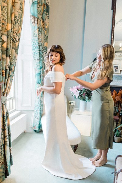 bride getting ready with bridesmaid