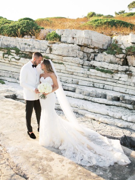 Bride and groom sea beach mountain Greek Greece exterior shot kissing couple cliff