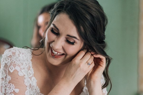 Bride getting ready by putting earrings on hair detail