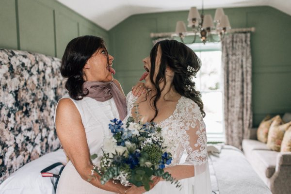 Bride and sister bridesmaid flowers bouquet laughing joking tongues