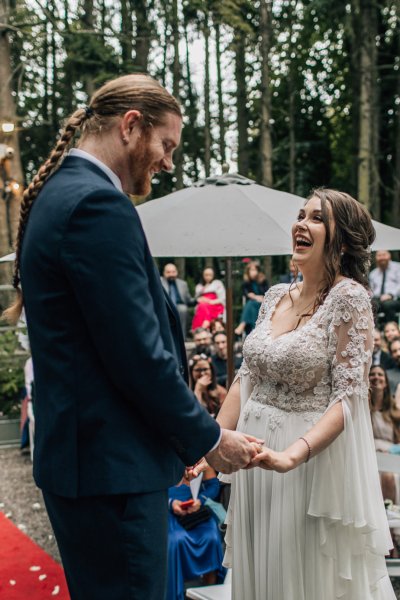 Bride and groom holding hands at wedding ceremony laughing