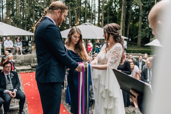 Bride and groom smile for the camera after being pronounced husband and wife wedding ceremony signing paper ribbon