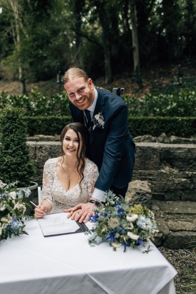 Bride and groom smile for the camera after being pronounced husband and wife wedding ceremony signing paper