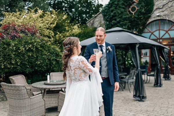 Bride and groom exterior wedding venue smiling cheers champagne