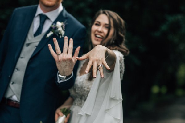 Bride and groom showing off their wedding bands rings