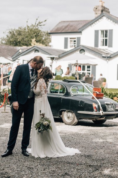 Bride and groom against wedding car castle in background flowers bouquet