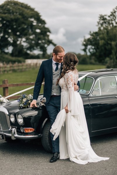 Bride and groom against wedding car castle in background