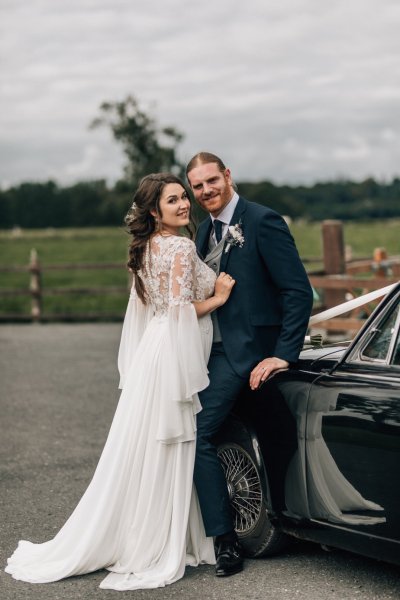 Bride and groom against wedding car