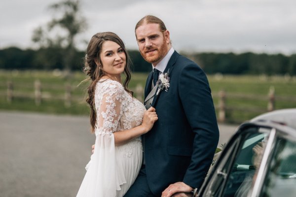 Bride and groom against wedding car