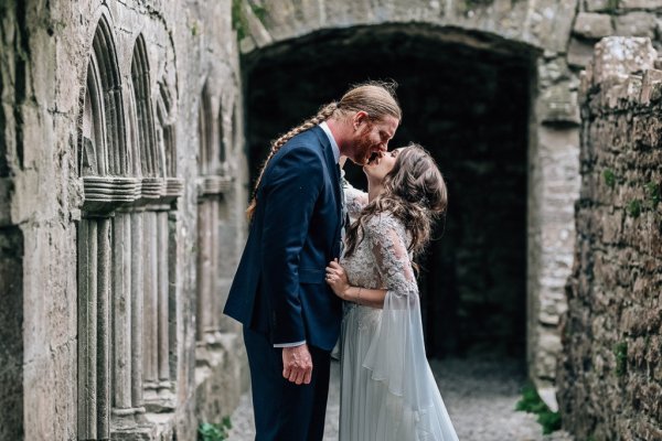 Bride reaching up to kiss groom exterior castle