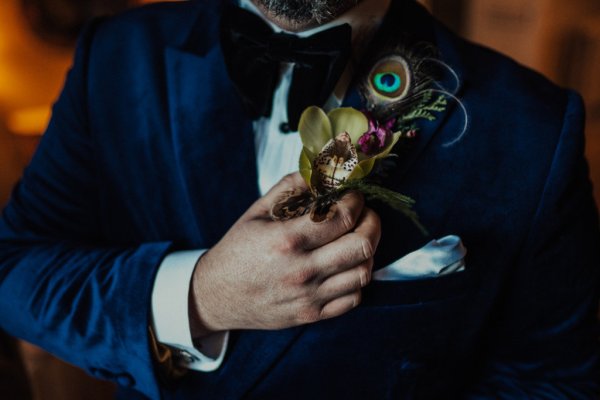 groom in tuxedo peacock feather