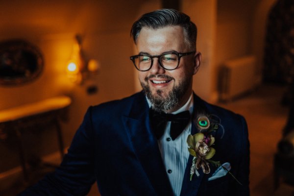 groom in tuxedo peacock feather