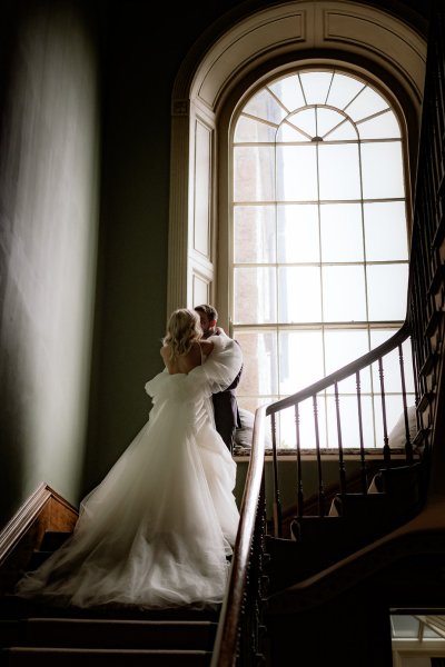 Long bridal gown stairs window groom