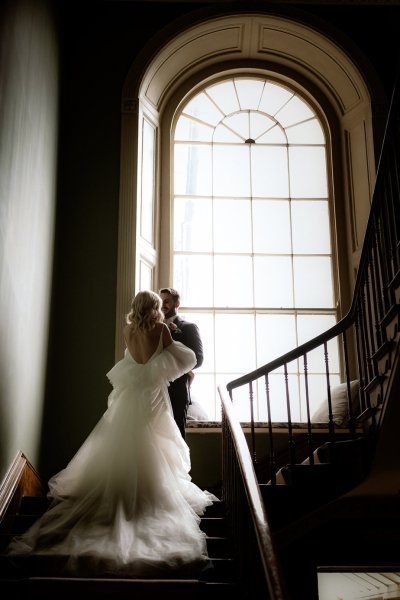 Long bridal gown stairs window groom