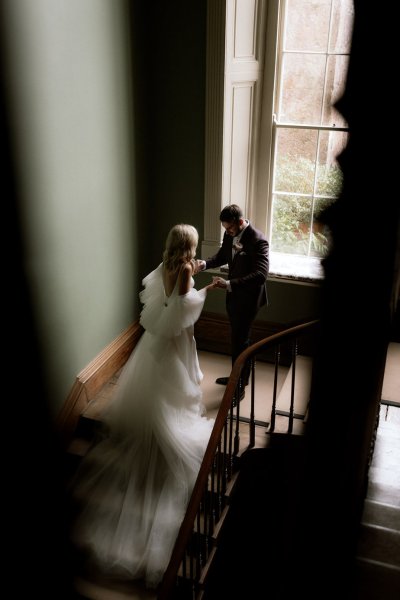 Long bridal gown stairs window groom