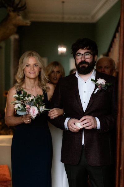 Bride groom in black attire suit dress flowers