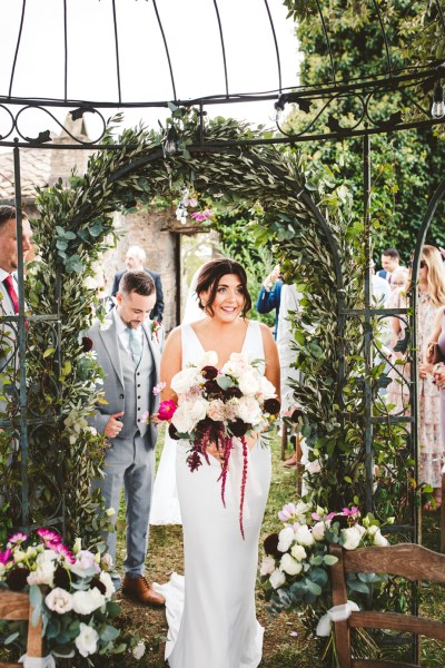 bride walks under arch