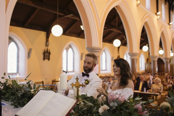 bride and groom light candle during ceremony in church