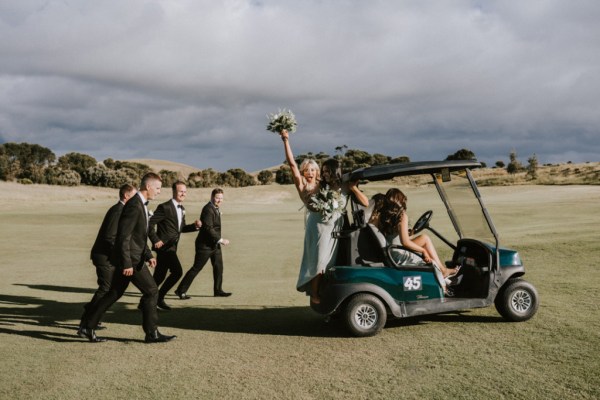 Bride and bridesmaids on golf cart being chased by groomsmen