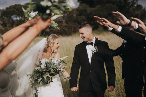 bride and groom couple under arch from hands