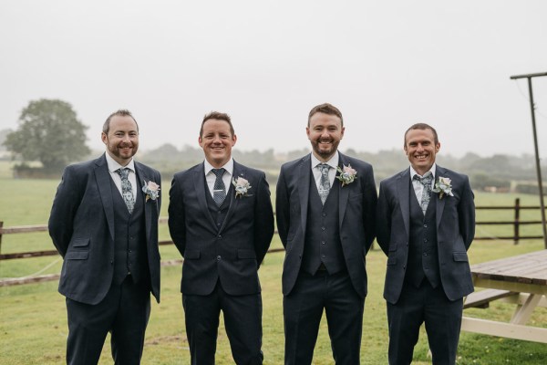 Groom groomsmen exterior farm forest green grass rainy day smiling