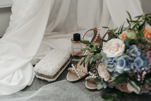 Close up detail of perfume heels roses bouquet of flowers dress beaded diamond purse