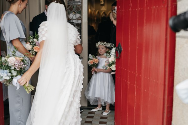 Bride holding bouquet of flowers little girl flower headband exterior church