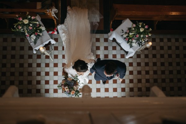 Over heads bride and groom inside church / chapel flowers ceremony candles