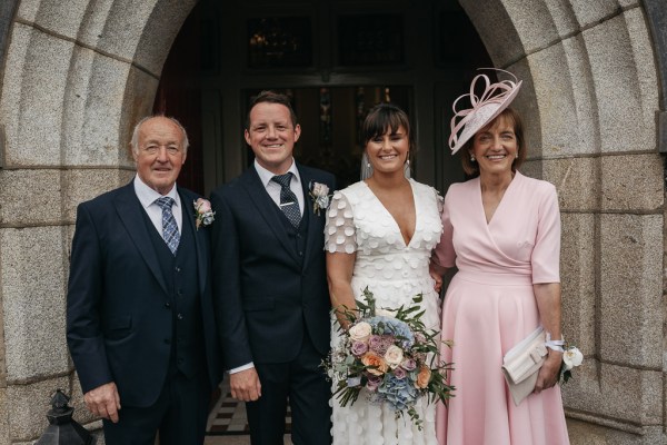 Bride groom family mother father bouquet of flowers roses outside exterior chapel/church