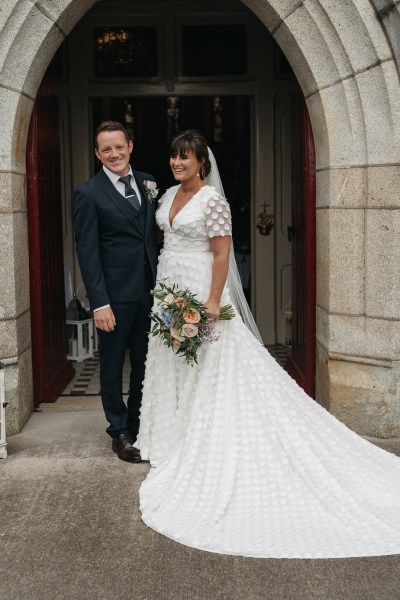 Exterior bride and groom standing outside chapel church