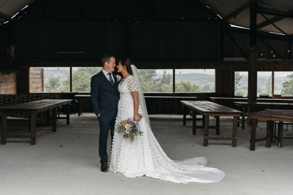 Bride and groom looking at each other touching nose bouquet of flowers