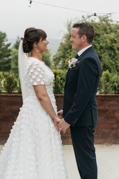 Bride looking at groom suit pink rose dress detail exterior