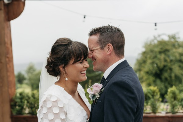 Groom laughing with bride exterior pink rose